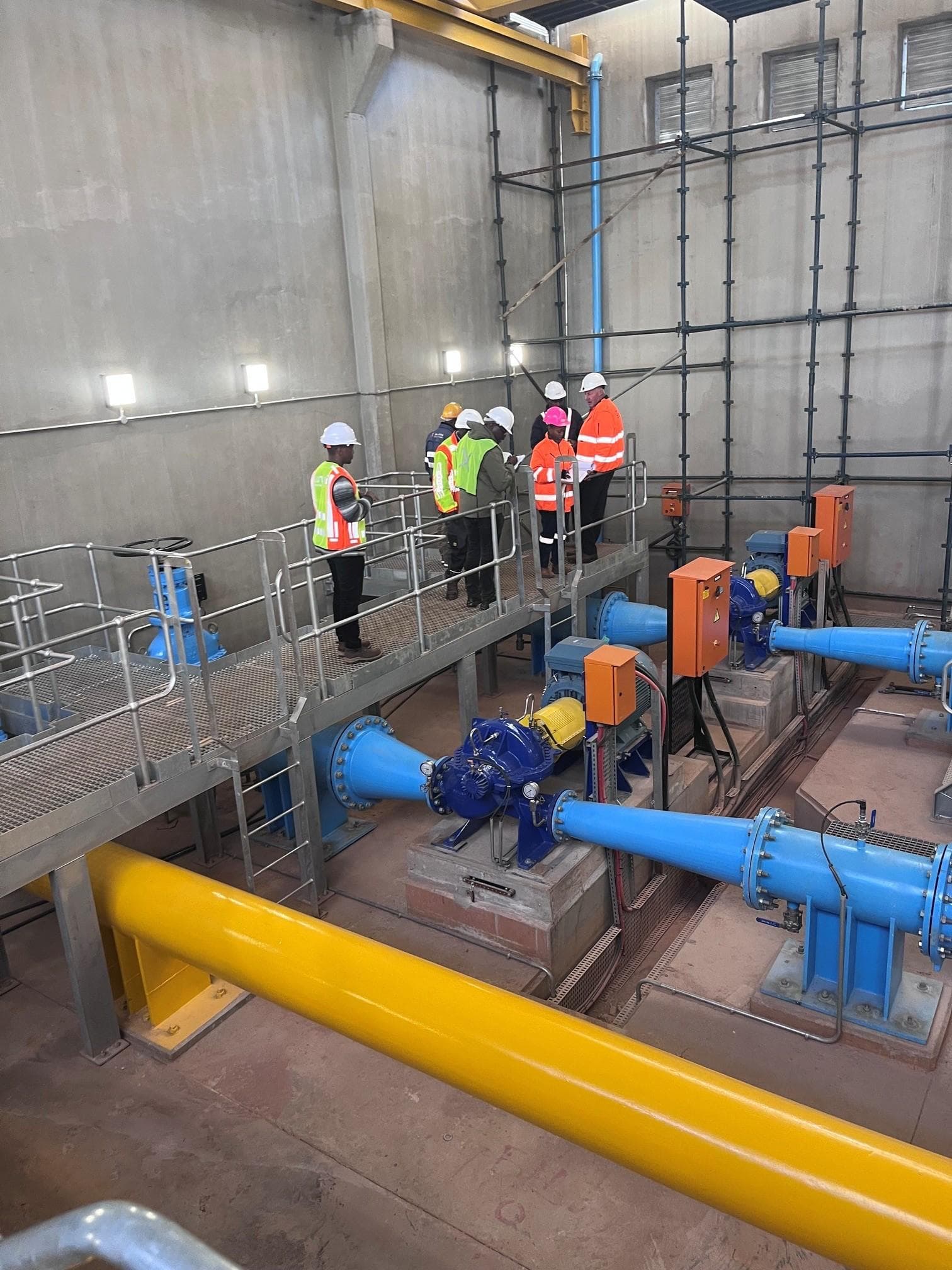 Engineers on the gantry above blue pump sets in the Crosby pump station